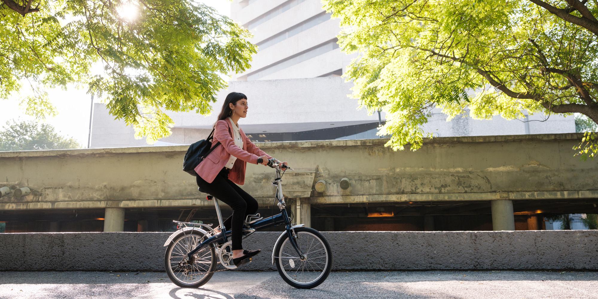 Frau auf dem Fahrrad im Hintergrund zwei Bäume