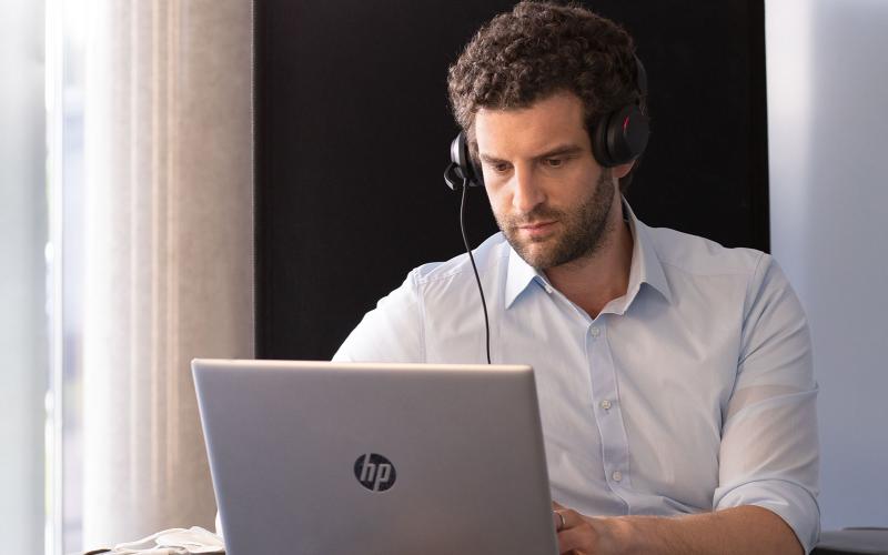 Junger Mann mit Headset vor Laptop