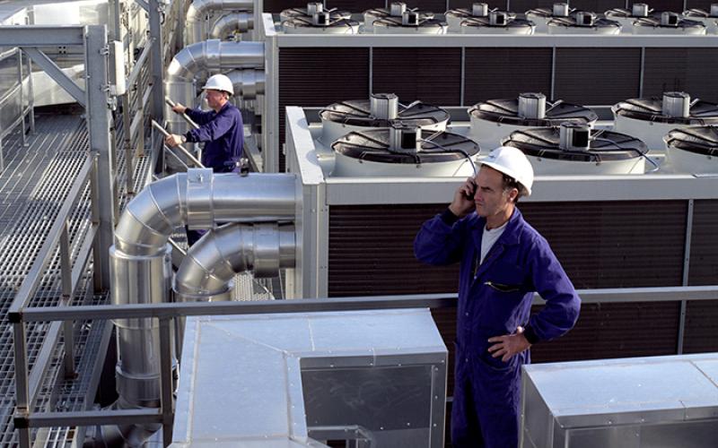 Arbeiter vor Industriekälteanlagen auf einem Dach