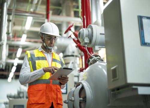 Mann an Ipad vor Heizungsanlage